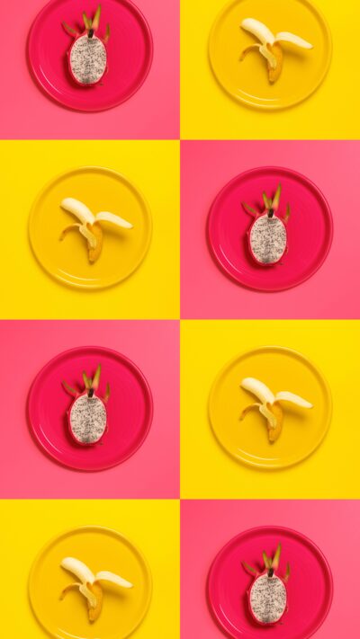 Repeating pattern of dragon fruit on pink plates and bananas on yellow plates.