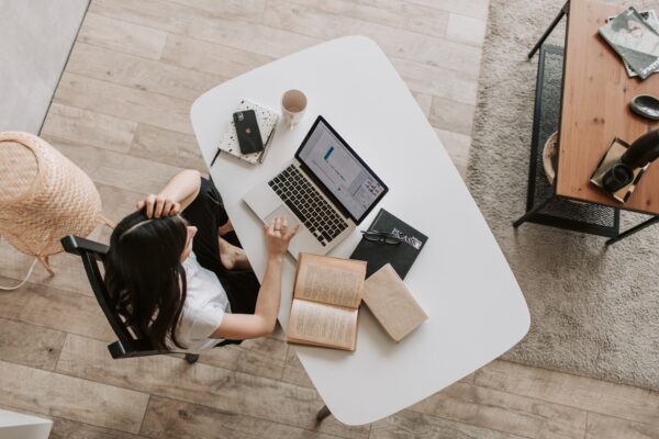 Overhead view of a frustrated woman working on a laptop at a desk.
